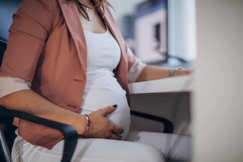 A pregnant person sitting at a desk

Description automatically generated